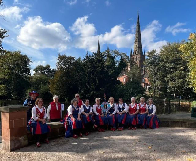 the group seated in front of the tree lined dam with the cathedral in the background